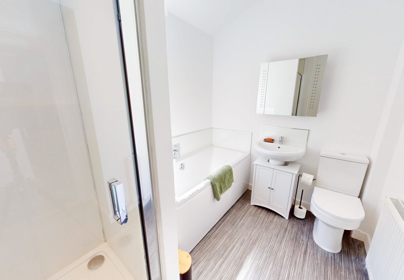 Modern white bathroom with a bath, glass shower enclosure, vanity unit, mirrored cabinet and toilet